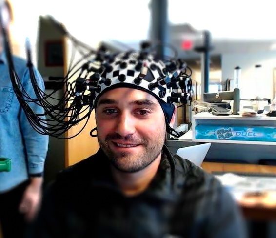 Adam wearing an EEG cap with electrode wires in the lab