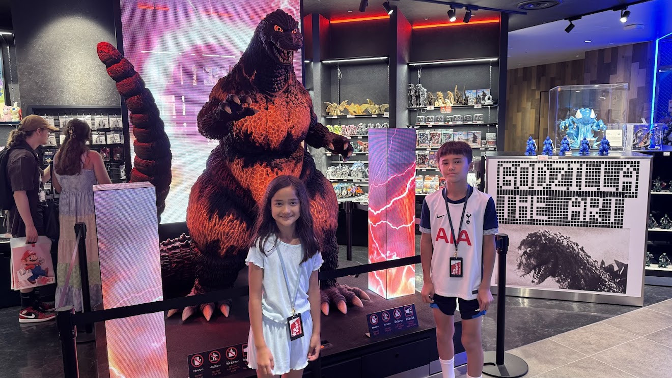 My son and daughter posing with a giant Godzilla statue at a Godzilla store