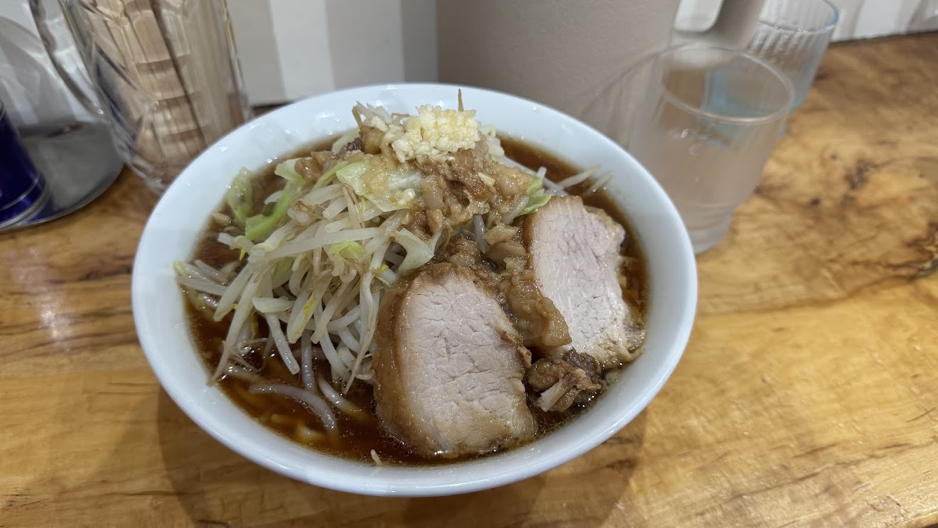 A bowl of Jiro-style ramen topped with a pile of bean sprouts, thick slices of chashu pork and garlic