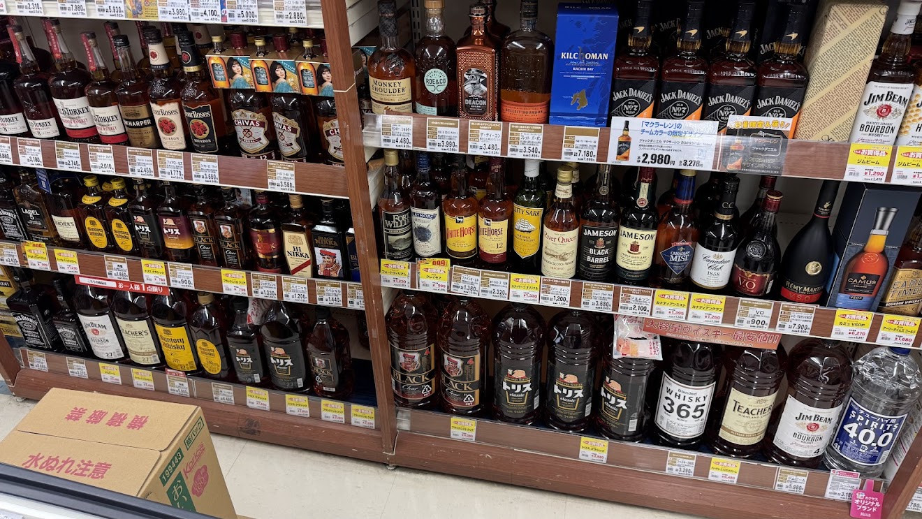 Shelves of Japanese whisky in a liquor store, including Suntory Torys and Black Nikka bottles